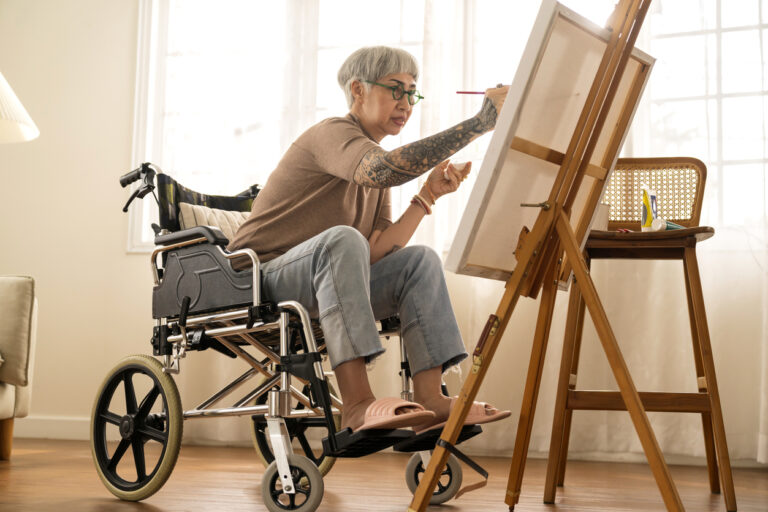 old senior asian female tattoo using art therapy while his legs is injured at home,asian elder woman spend recovering of her leg is getting better with painting canvas art in living room at home